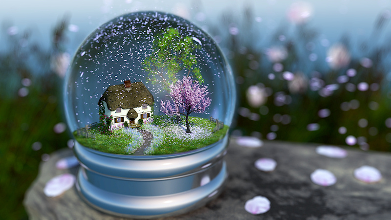 Inside a 'snow globe' is a spring landscape with a cottage overshadowed by maple and cherry trees. The surrounding grassy field is filled with spring flowers, snapdragons and cornflowers in pastel colors. Roses and ivy climb the wall of the little house. The cherry tree is in full bloom, and instead of snow there are cherry blossoms swirling around in the globe and blanketing the grass.